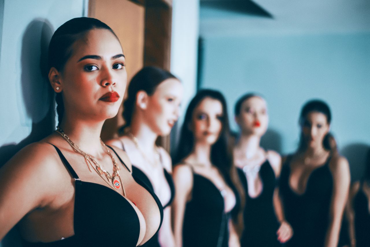 A diverse group of women posing in fashionable black outfits indoors, showcasing elegance and style.